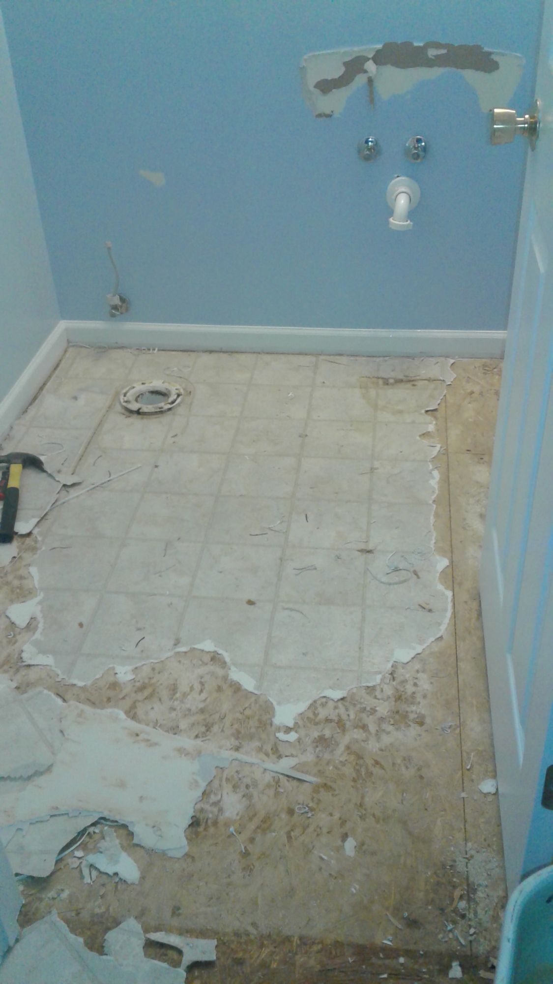 A bathroom with a tiled floor and blue walls is being remodeled.