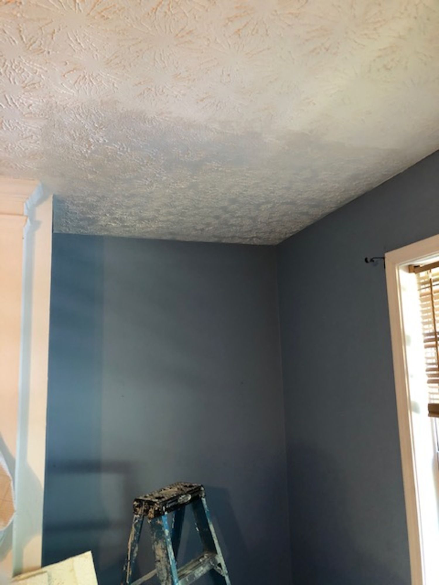 A room with blue walls and a ladder in the corner.