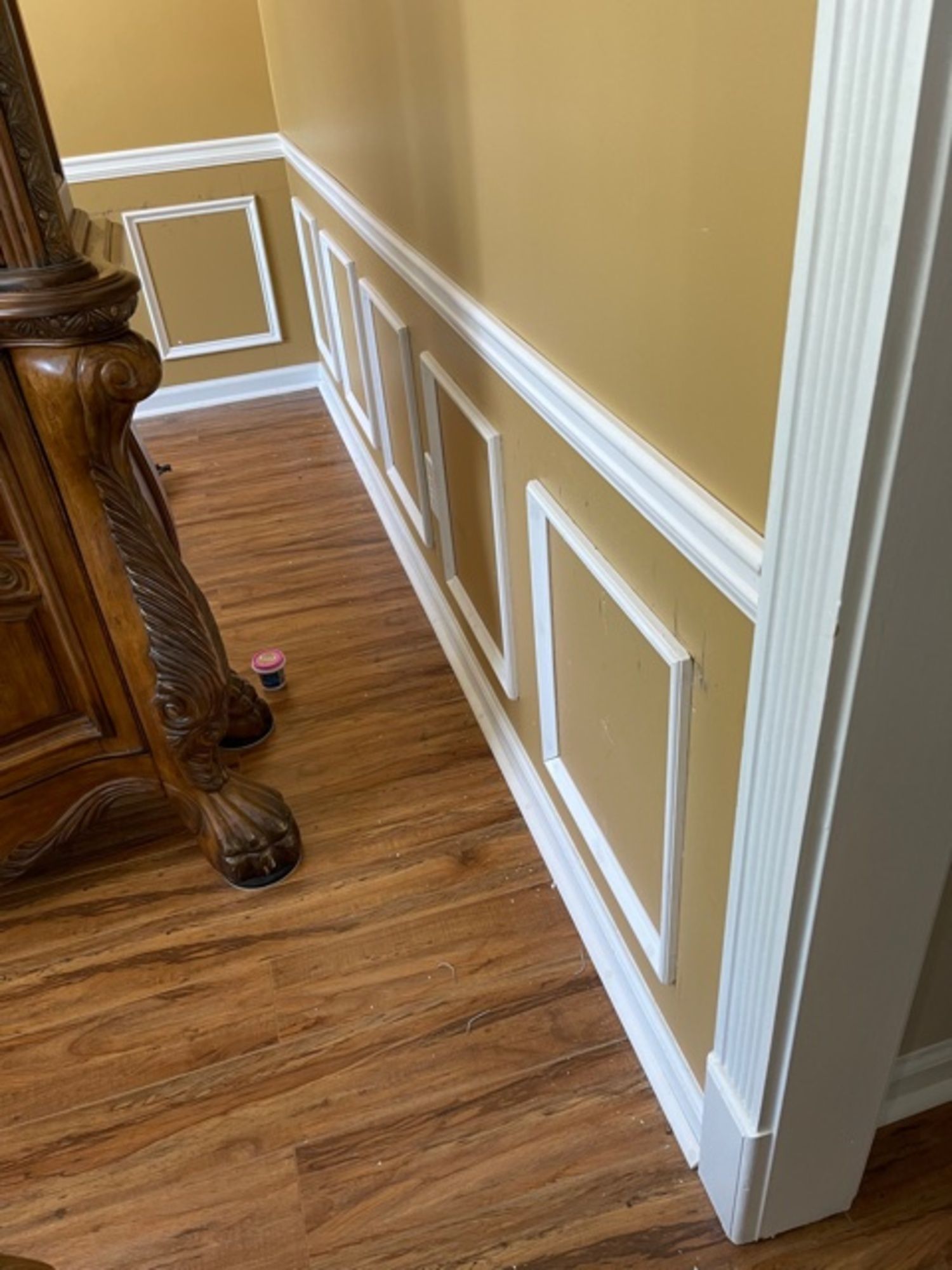 A hallway with hardwood floors and yellow walls with white trim.