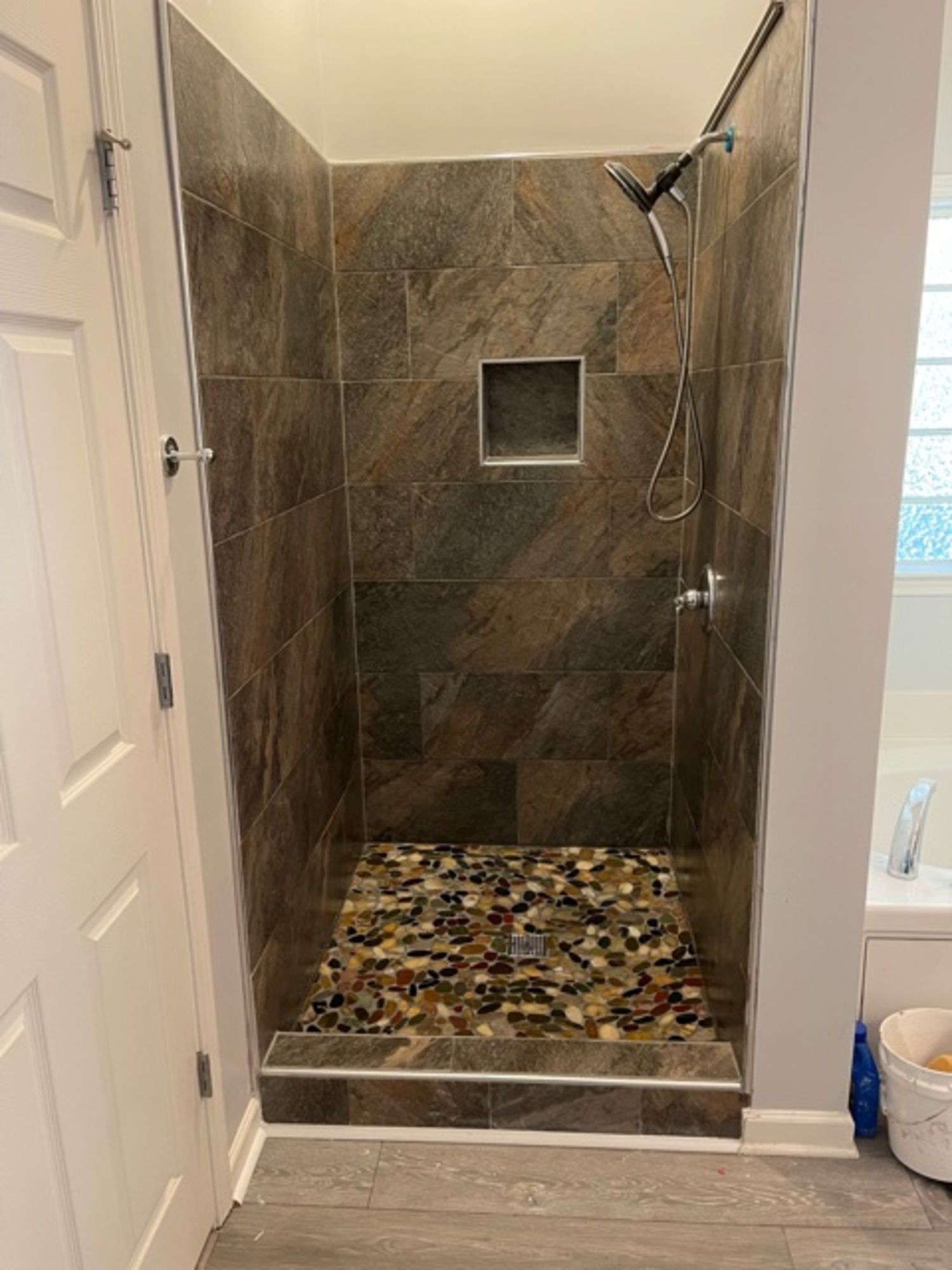 A bathroom with a walk in shower with a glass door.