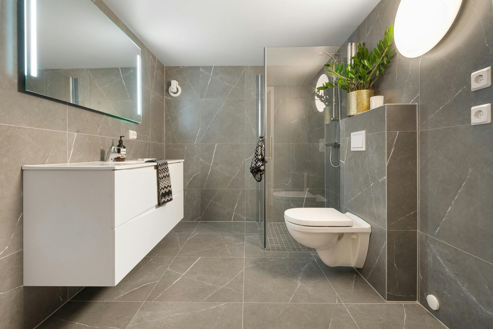 A bathroom with a toilet , sink , mirror and walk in shower.