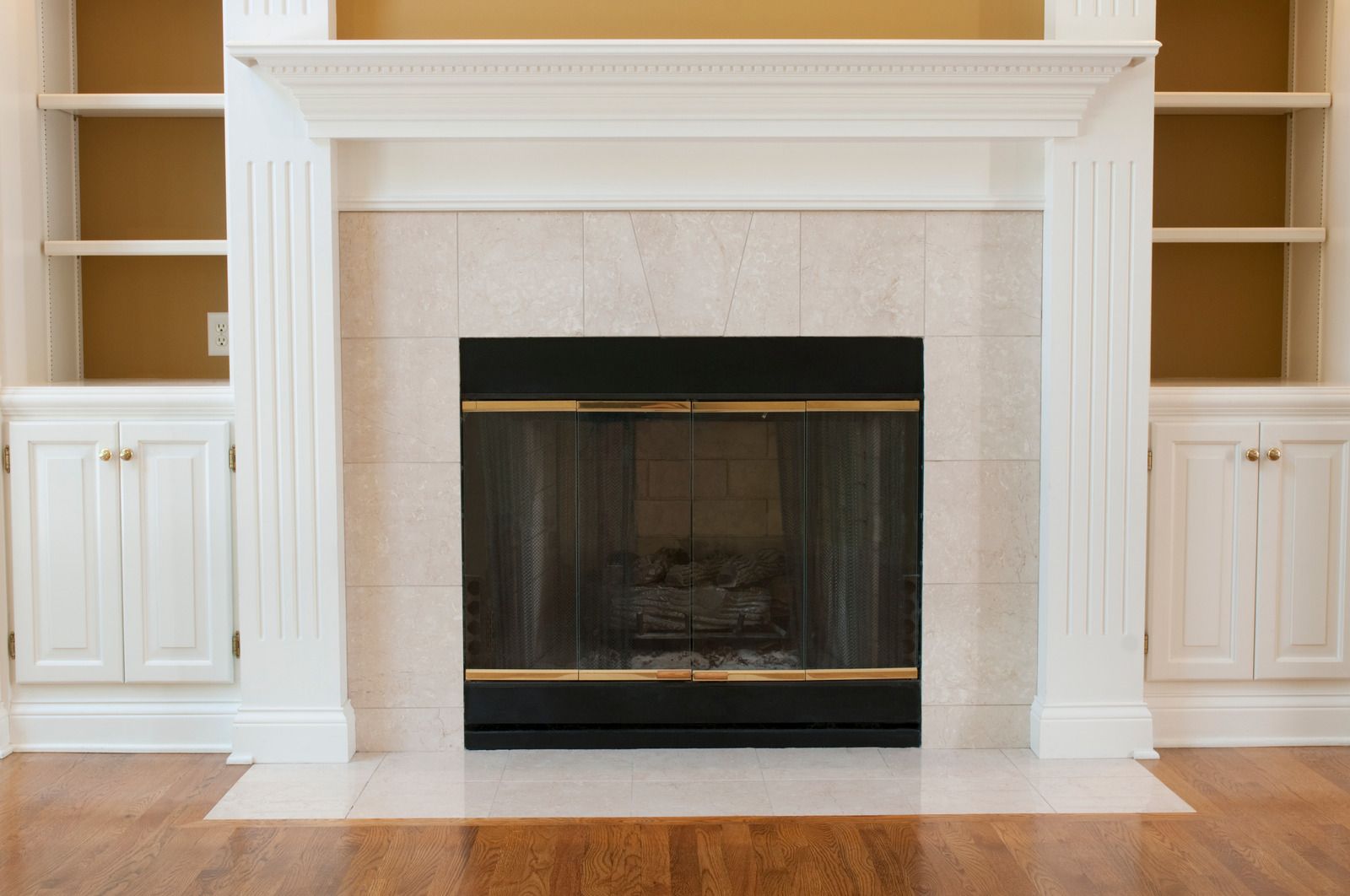 An empty living room with a fireplace and shelves