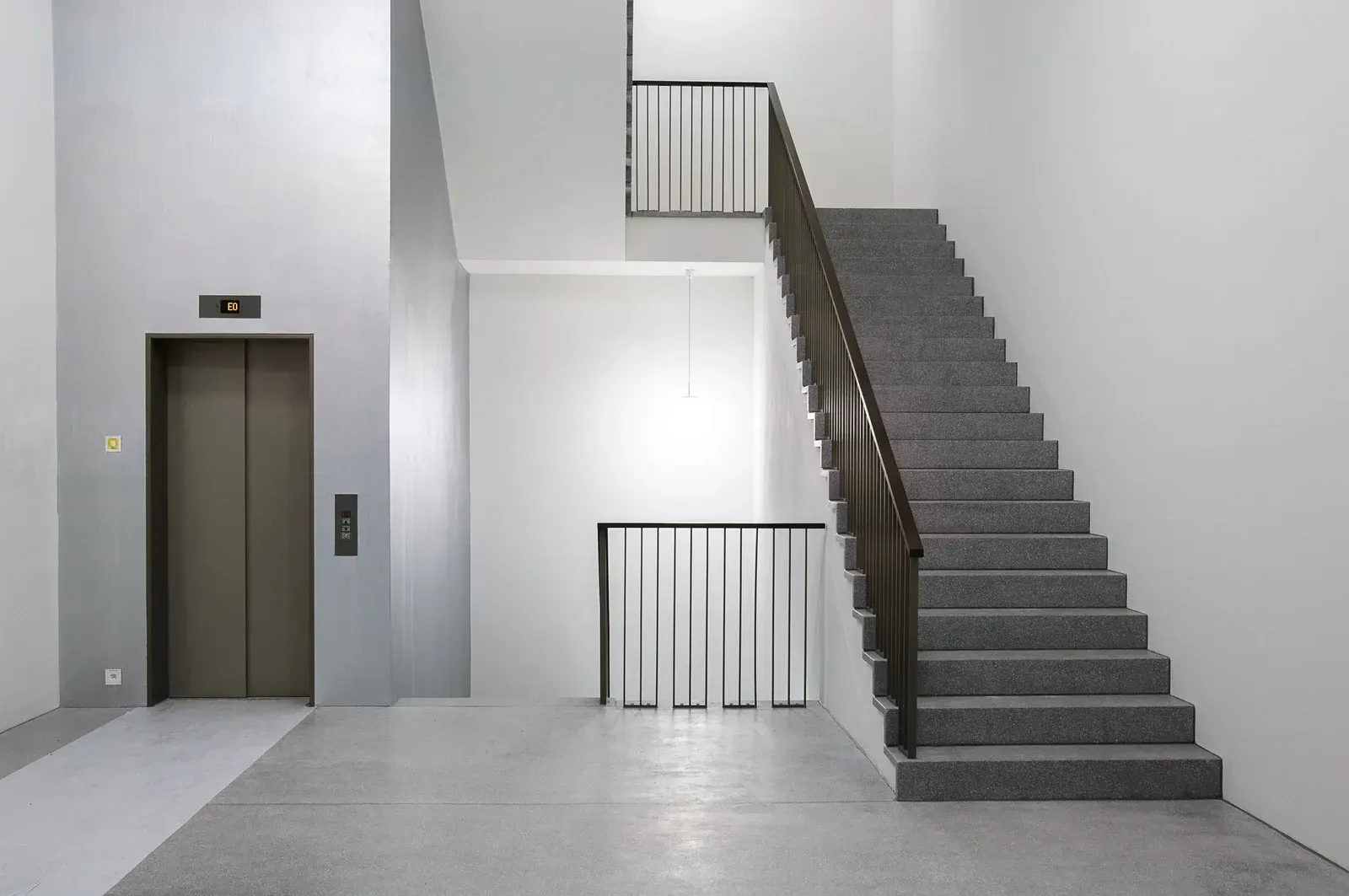 A staircase in a building with an elevator in the background