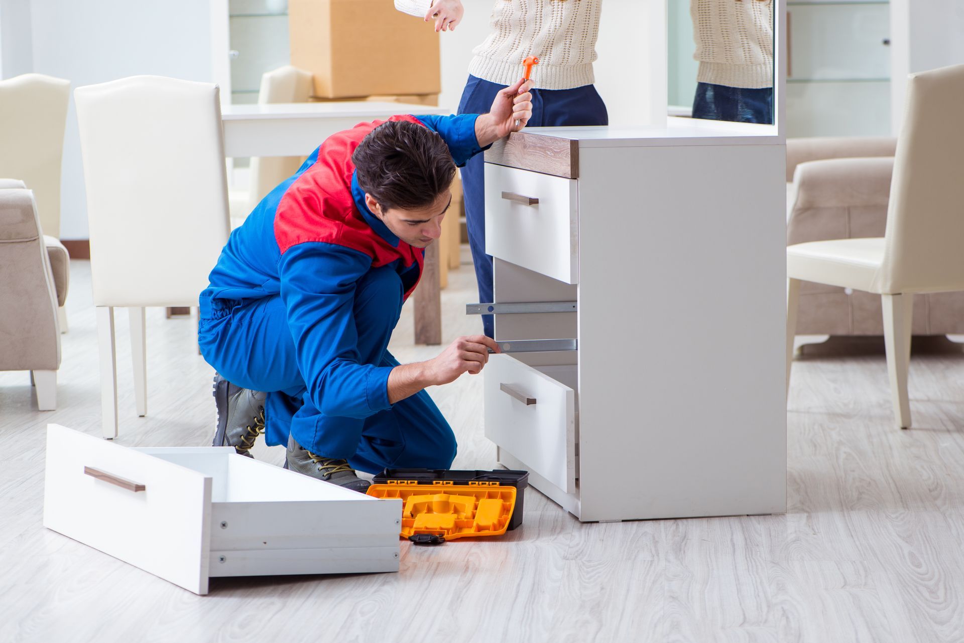 A man is fixing a drawer in a living room.