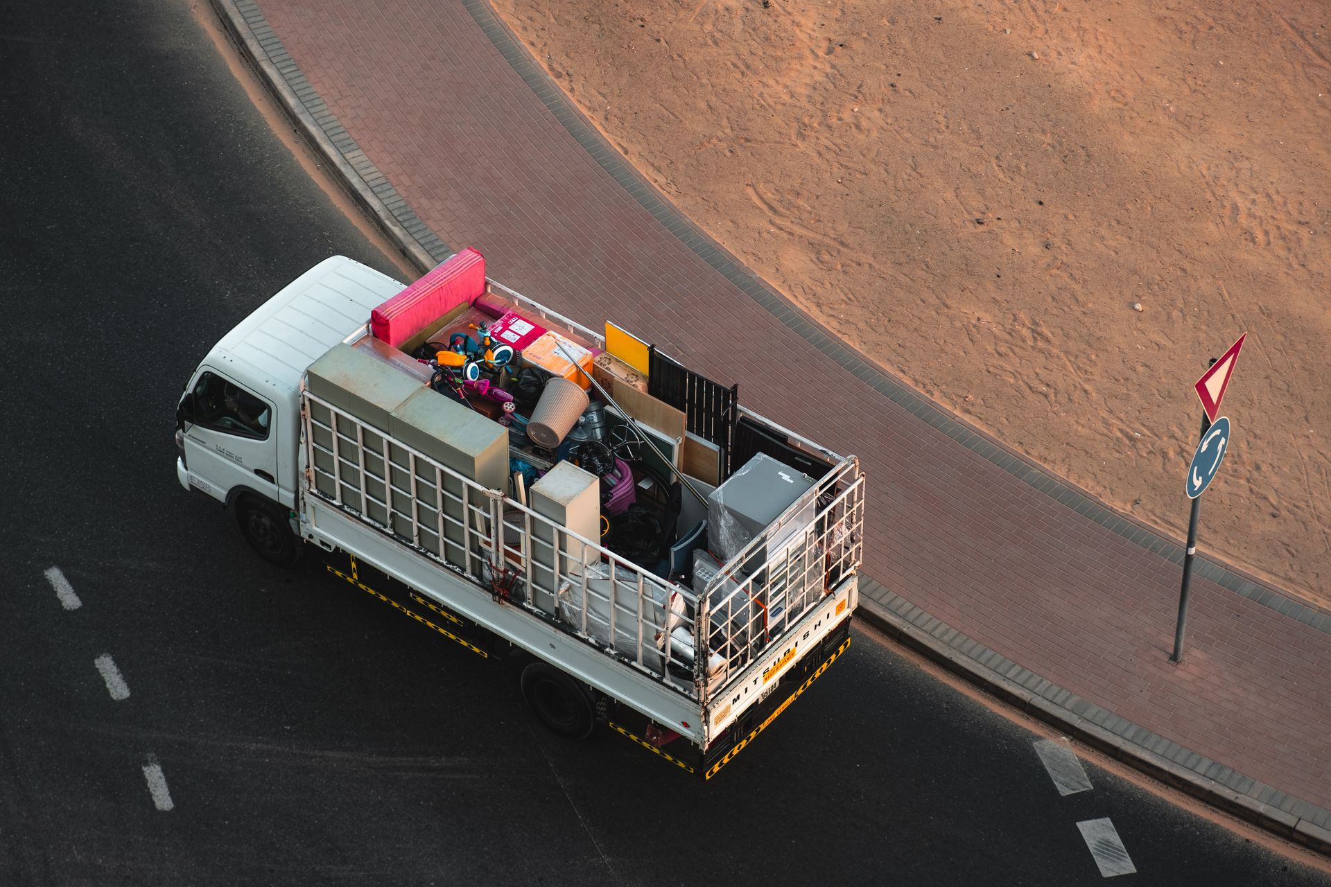 An aerial view of a moving truck filled with furniture driving down a street.
