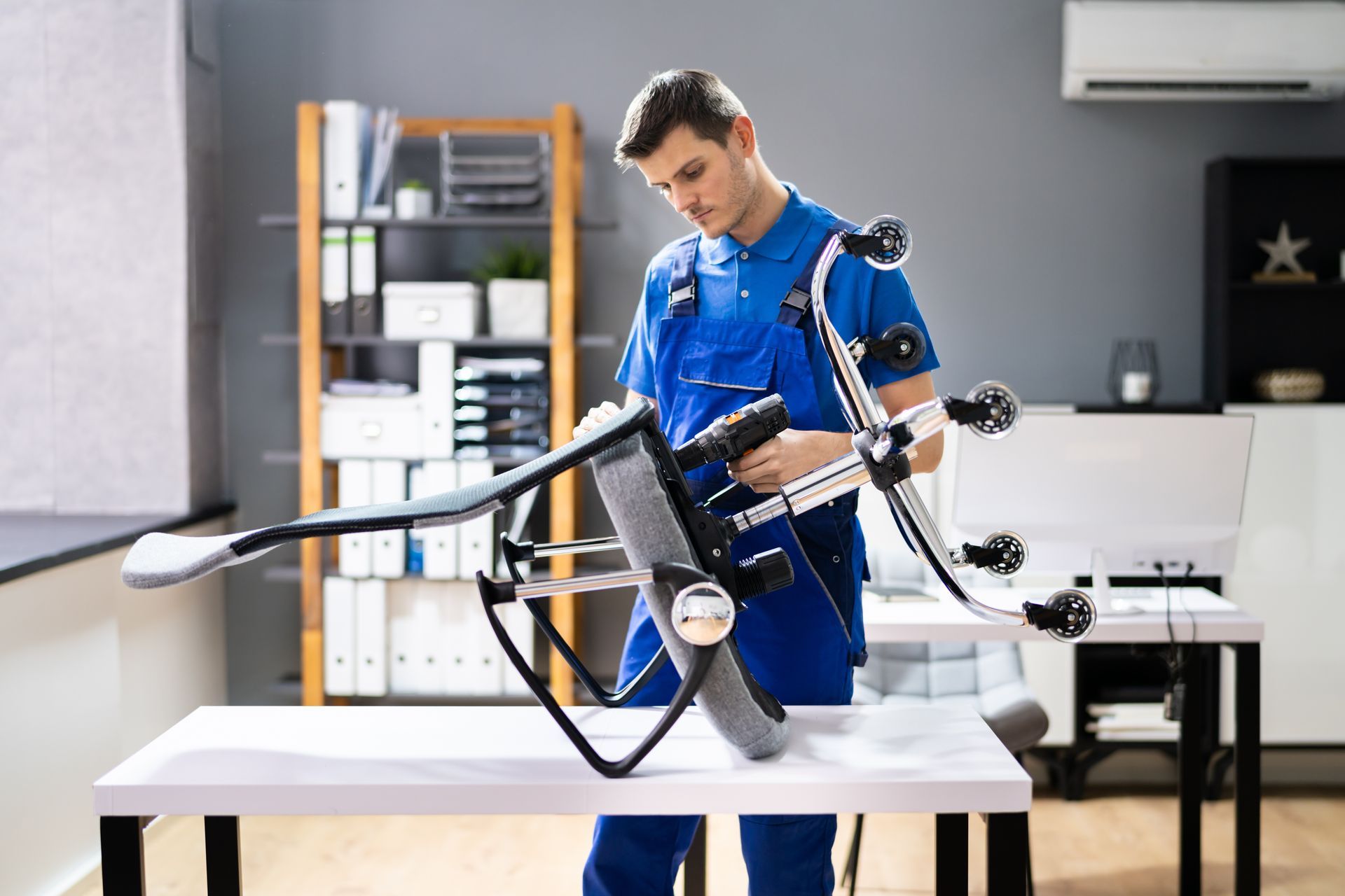 A man is fixing a chair on a desk in an office.