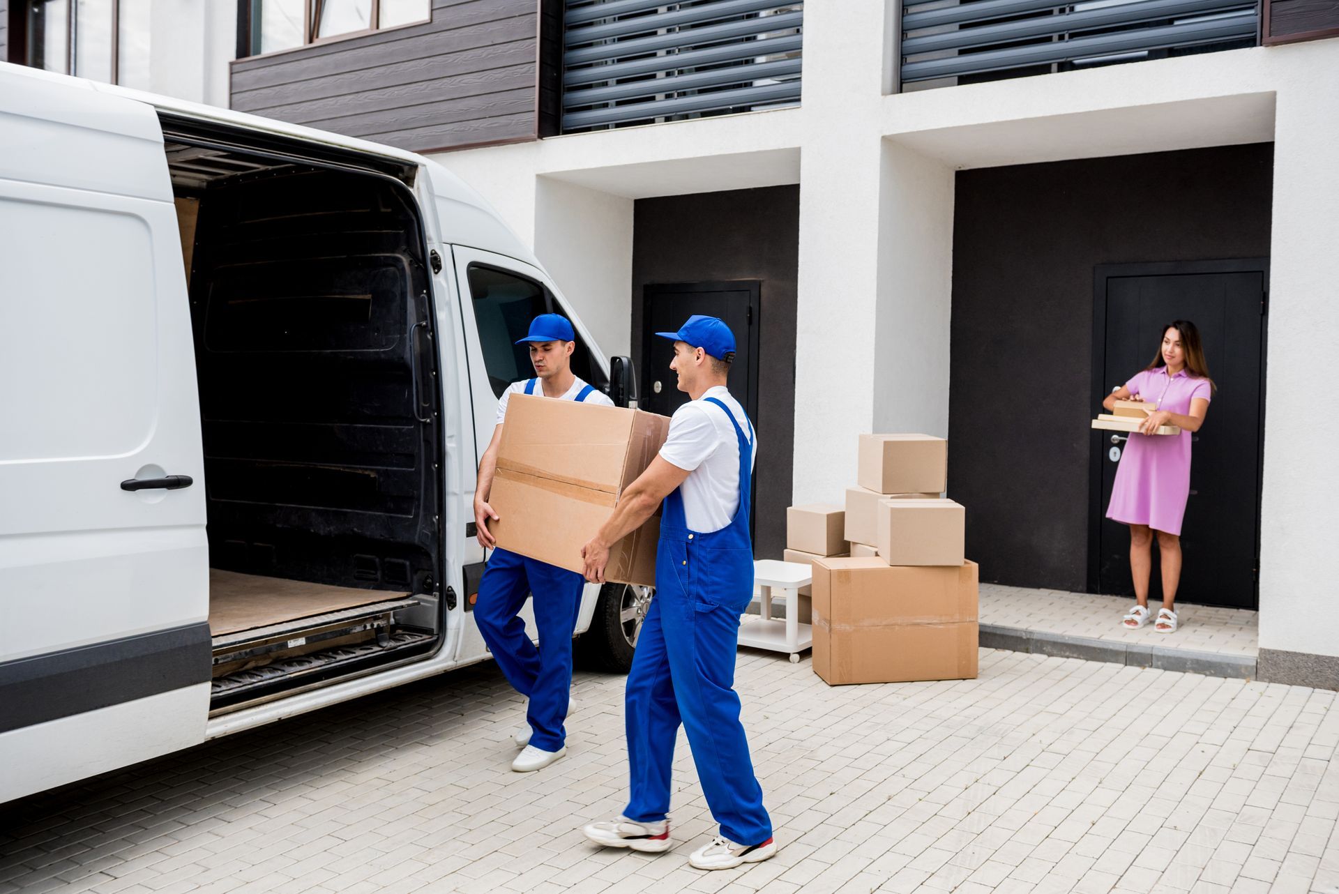 Two men are carrying boxes out of a van.