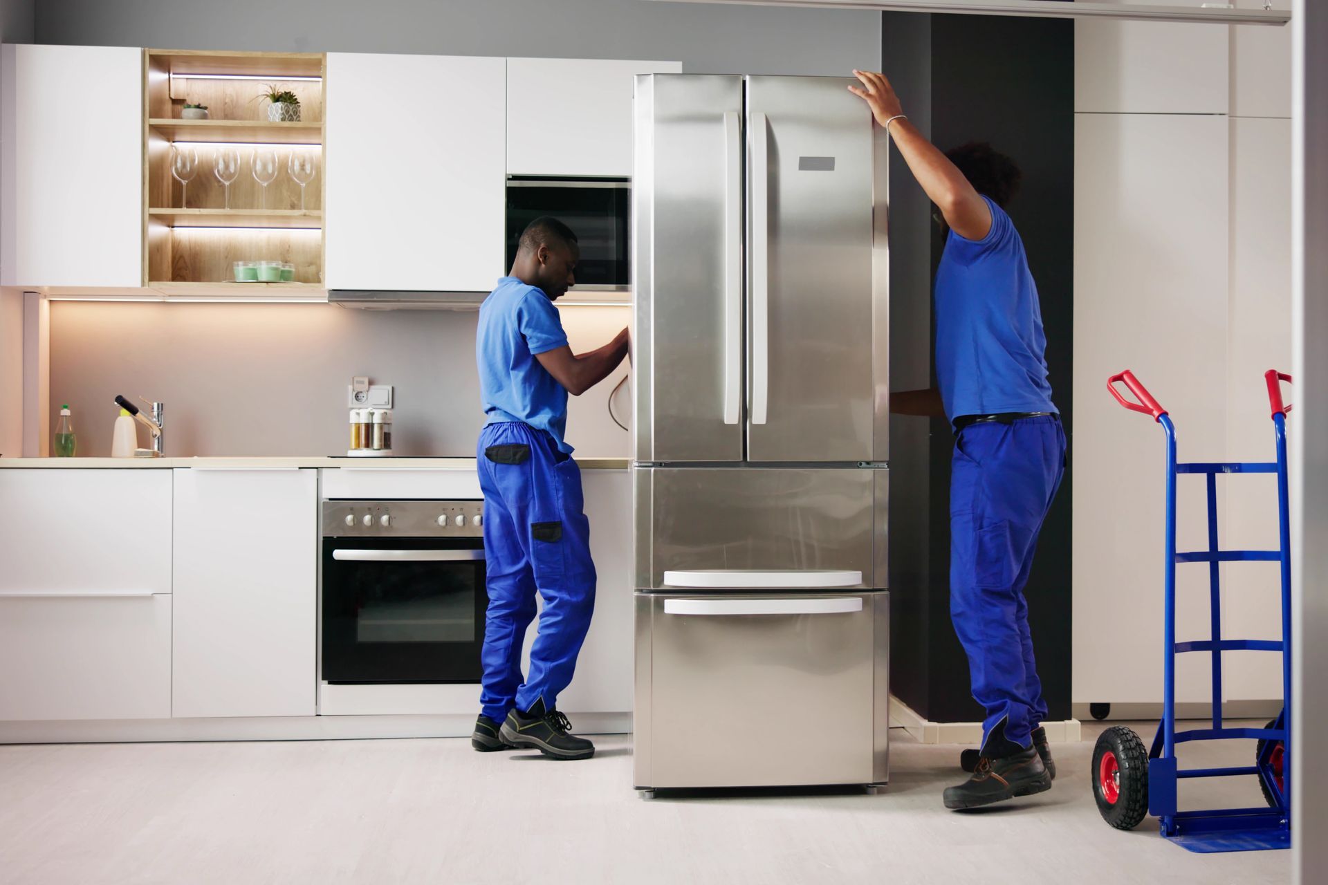 Two men are installing a refrigerator in a kitchen.