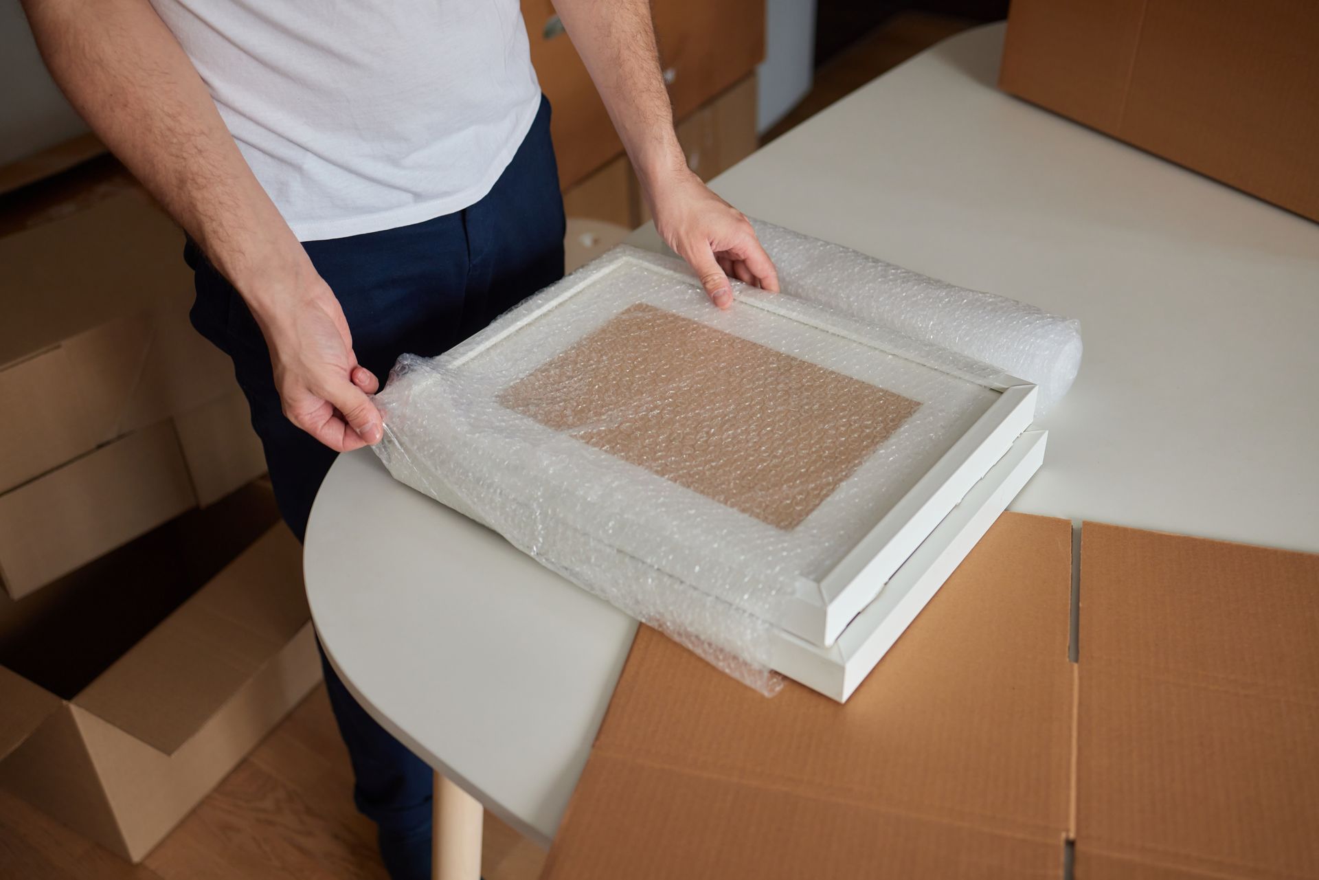 A man is putting a picture frame on a table.