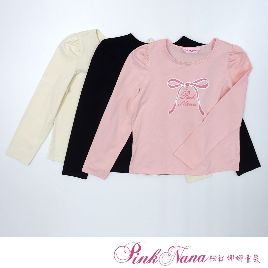 戴著粉紅色貝雷帽、黑色蝴蝶結上衣和粉紅色格子裙的女孩對著鏡頭微笑。