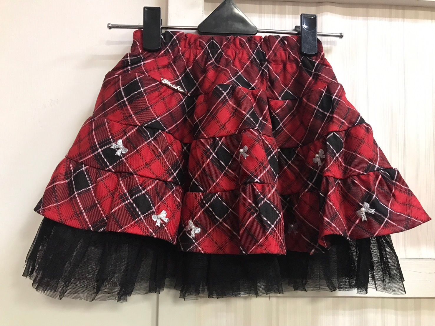 三個戴著紅色貝雷帽和裙子的女孩正在擺姿勢拍聖誕照片。