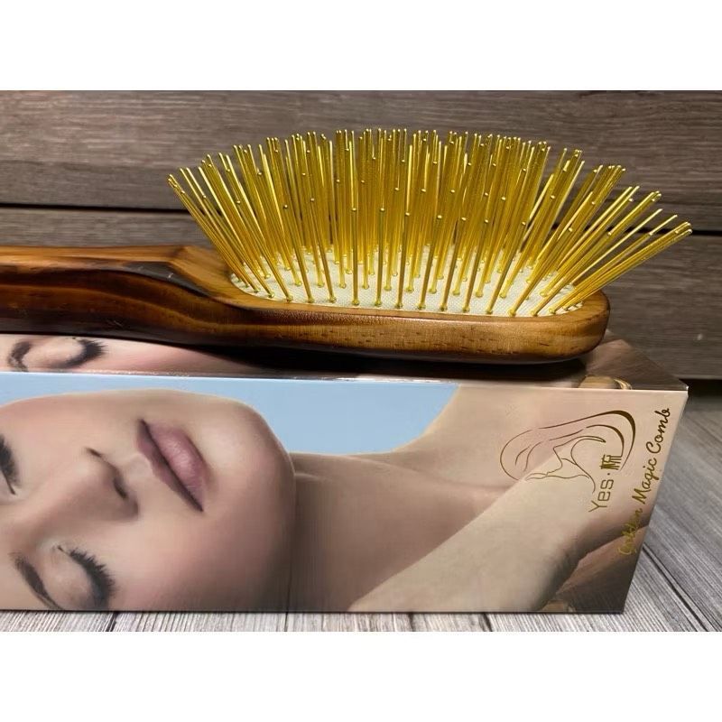 一把木柄金色刷毛的髮刷，放在黑布上，還有一個畫著女人臉的盒子。