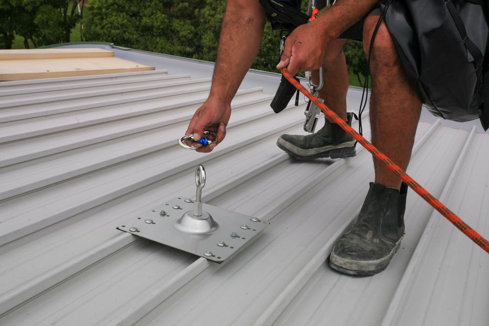 A Man Is Working On A Roof With A Rope — Roof & Guttering Solutions In Saratoga, NSW