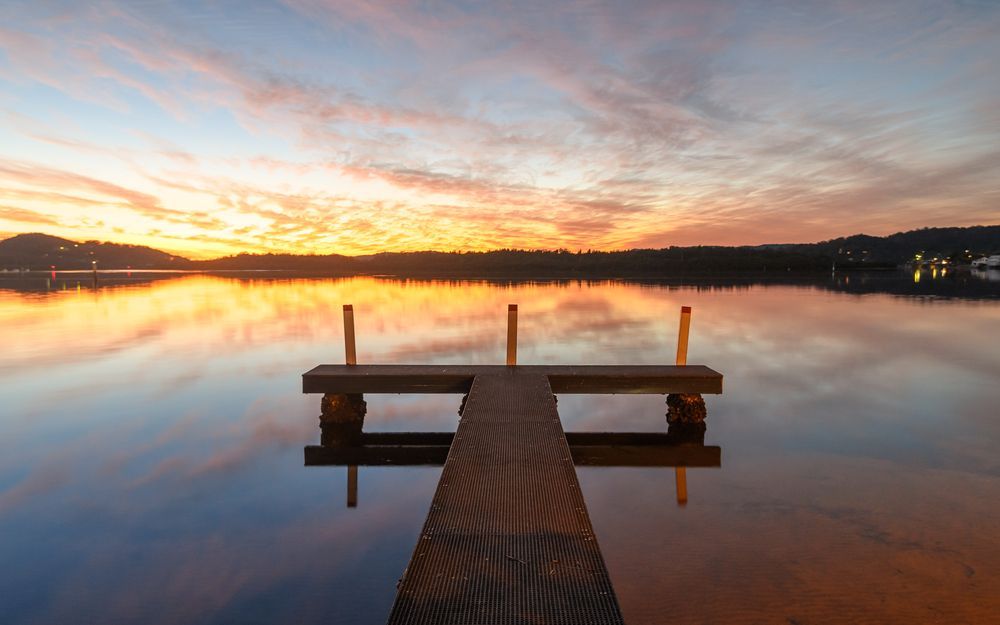 There Is A Dock In The Middle Of A Lake At Sunset — Roof & Guttering Solutions In Woy Woy, NSW