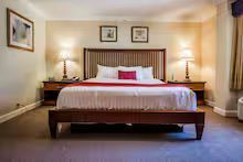 Hotel bedroom with a large bed, two nightstands, lamps, and artwork.