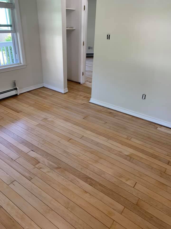 An empty room with hardwood floors and white walls.