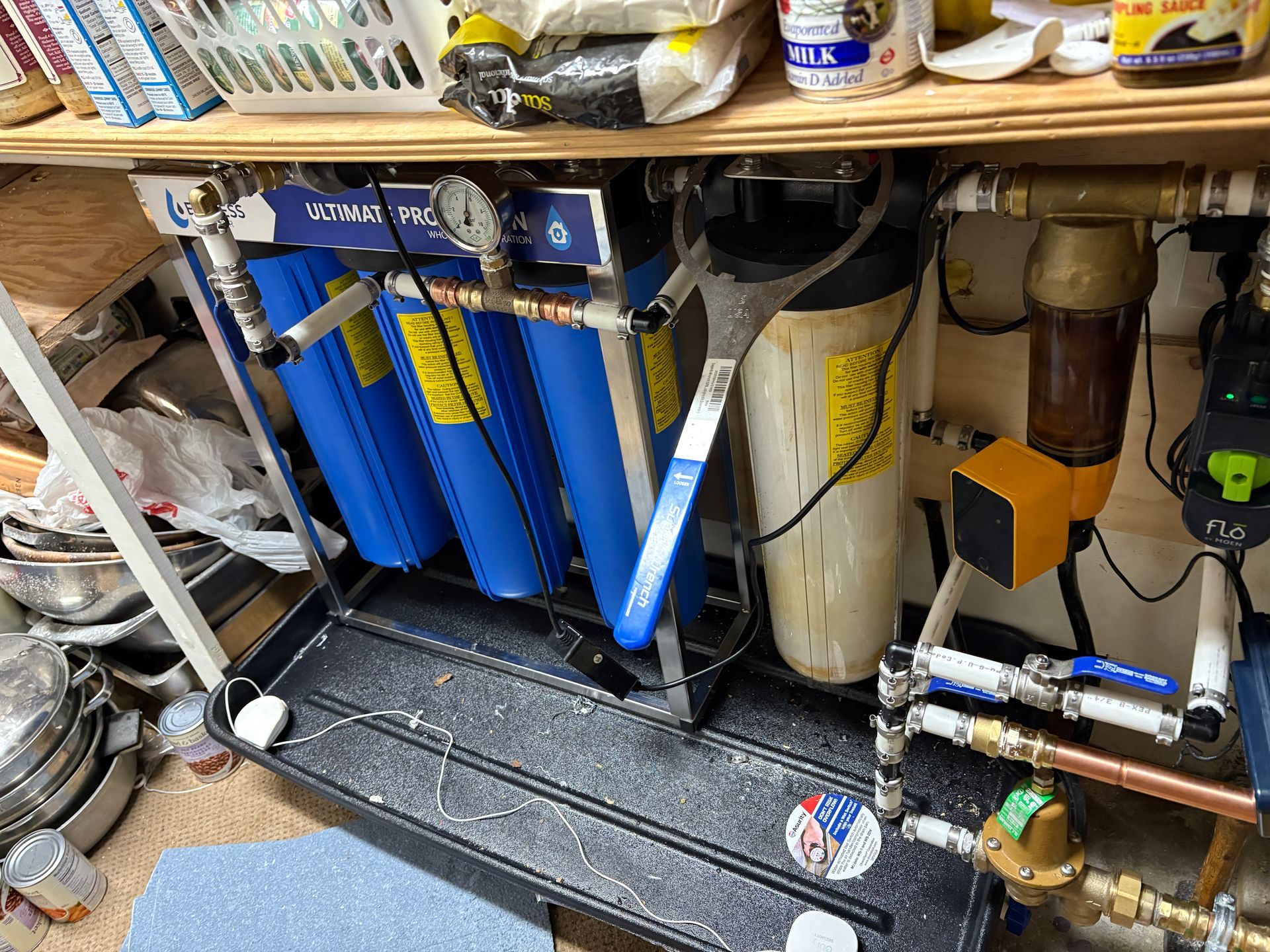 Water filtration system with blue and white filters, gauges, and a large wrench.