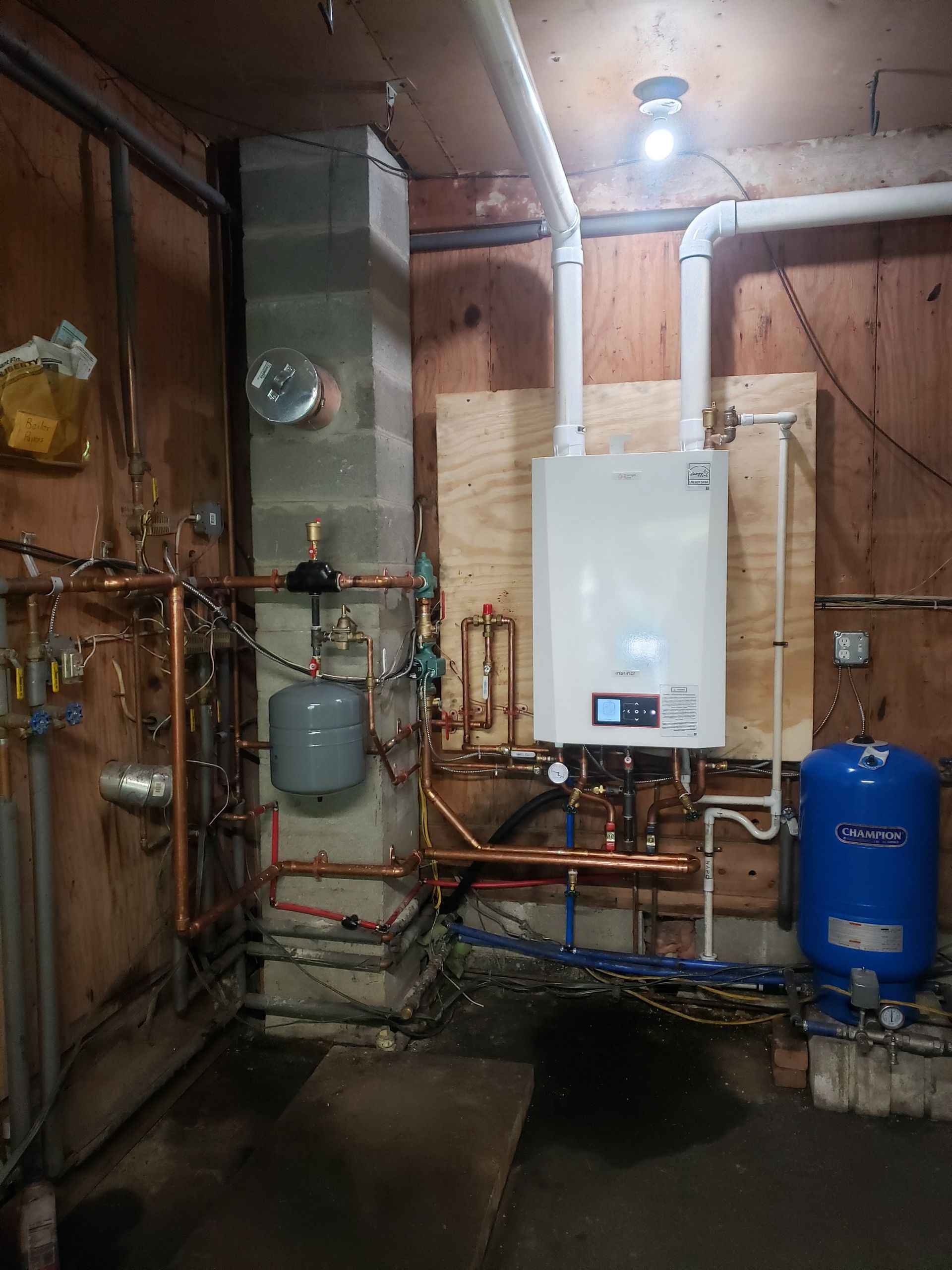 Plumbing system with boiler, water tank, and copper pipes in a basement.