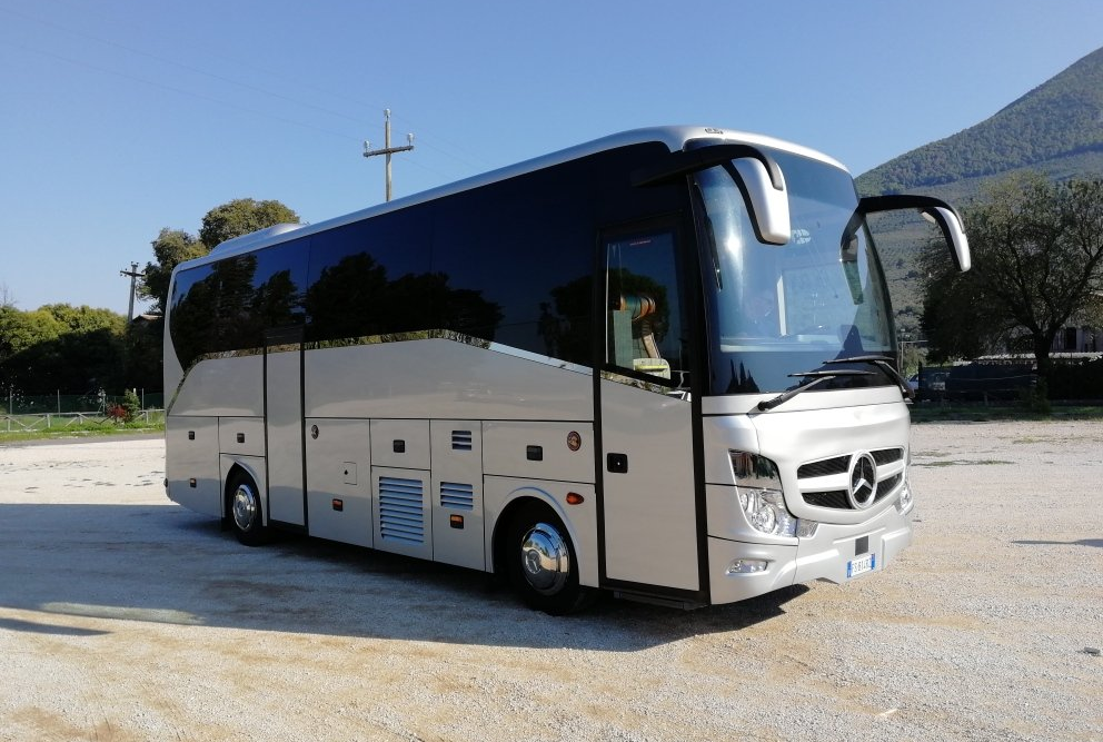 Autobus passeggeri argento e nero con porta aperta parcheggiato all'aperto.