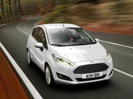 Ford Fiesta bianca in marcia su una strada curva.