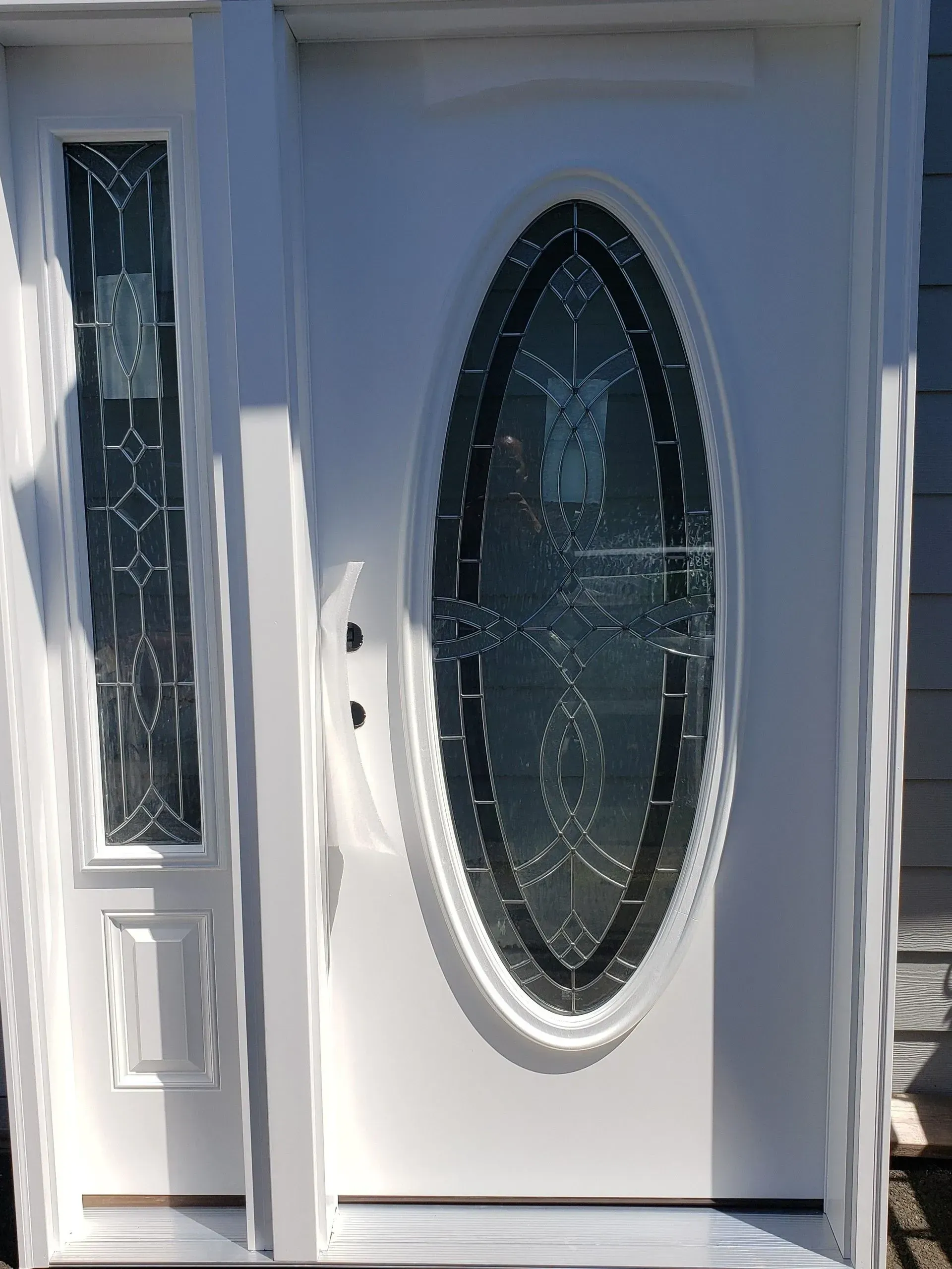 Two electricians working on an electrical panel outside a building. One holds a cable.