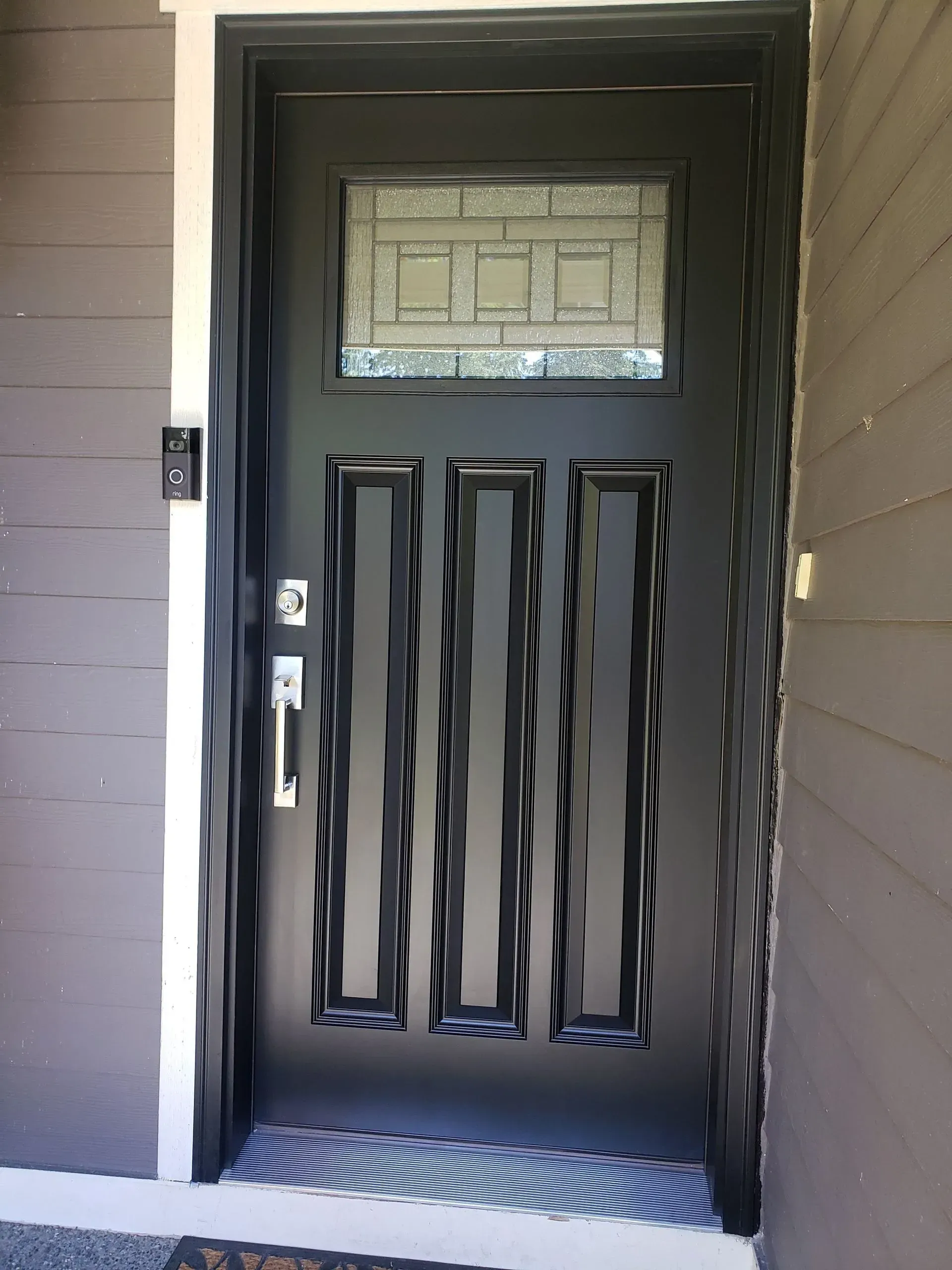 A person digs a trench in a backyard near a small excavator, a tree, and a house.