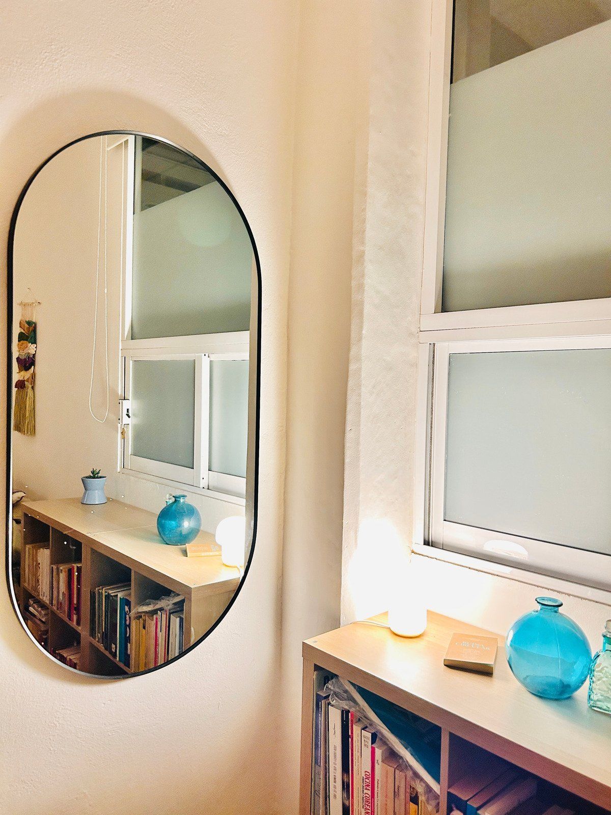 A person digs a trench in a backyard near a small excavator, a tree, and a house.