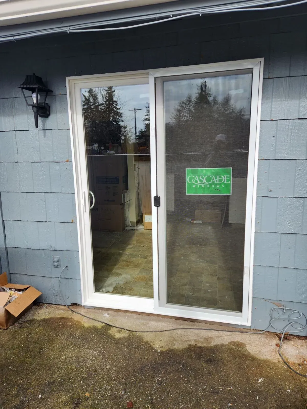 Trench dug in a grassy yard, leading to a house with black siding, and an electrical box.