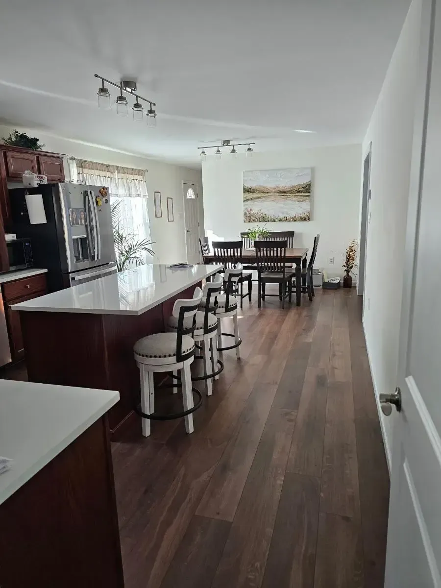 Kitchen with dark wood cabinets, large island with stools, and dining area.