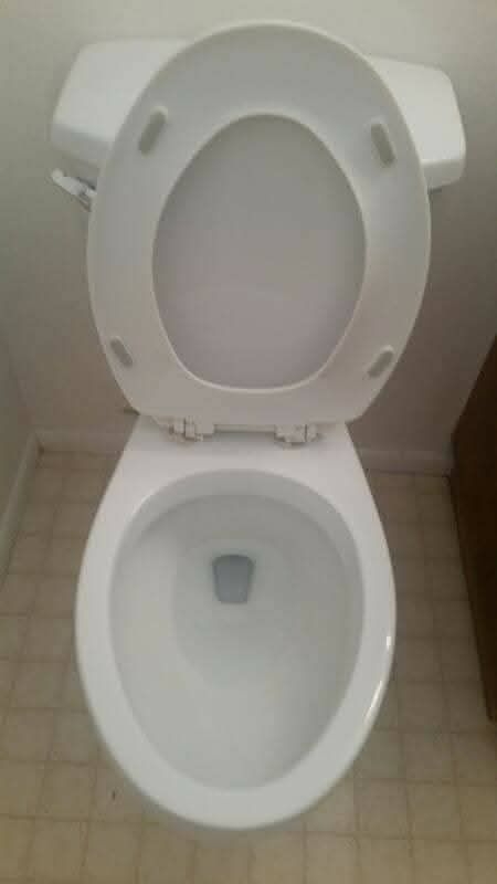 White toilet with the lid up, viewed from above in a bathroom.