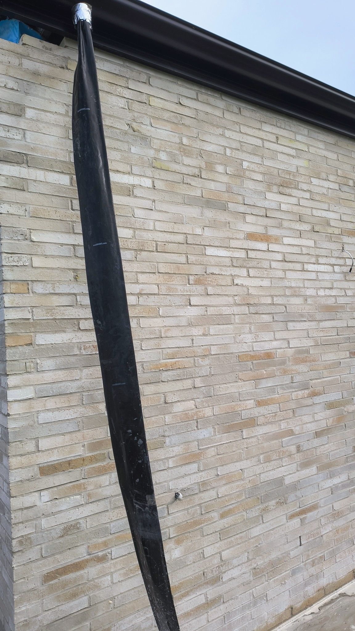 Black Downspout Against A Light Beige Brick Wall Under A Dark Brown Gutter — Bricks By Dre In Tallai, QLD