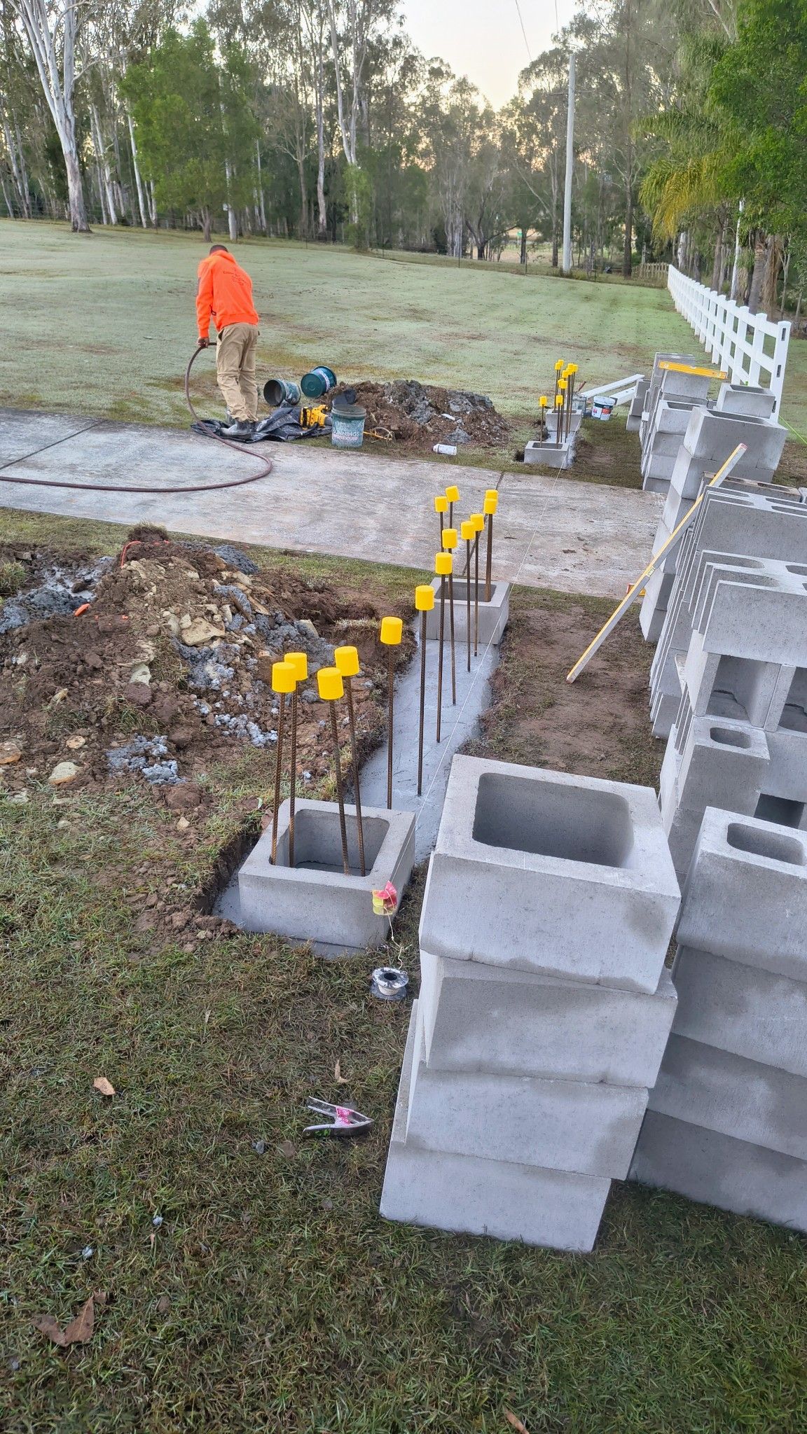 Construction Site With Concrete Blocks, Rebar, And A Worker In An Orange Vest — Bricks By Dre In Oxenford, QLD