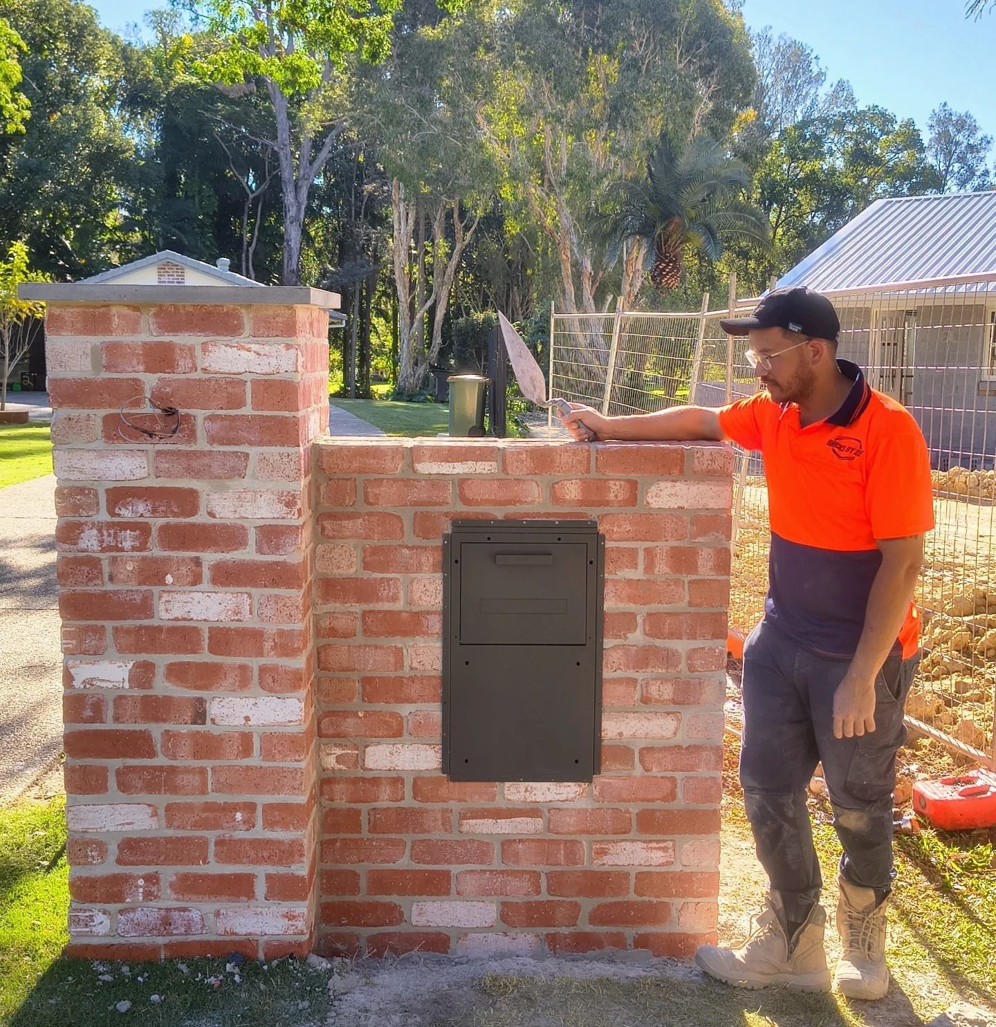 A man in work clothes stands next to a brick mailbox — Bricks By Dre In Oxenford, QLD