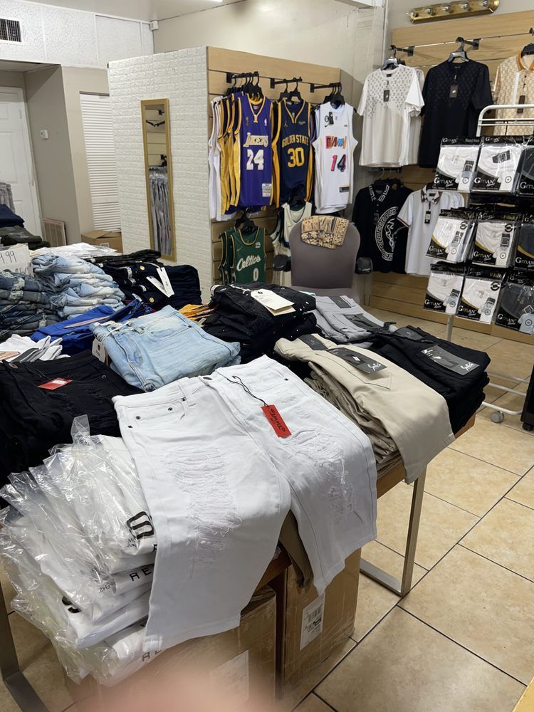 Clothing store interior with tables of jeans and shirts, jerseys on the back wall.