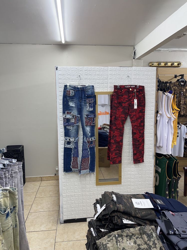 Jeans displayed on a white wall in a store. Blue and red patterned jeans are visible.