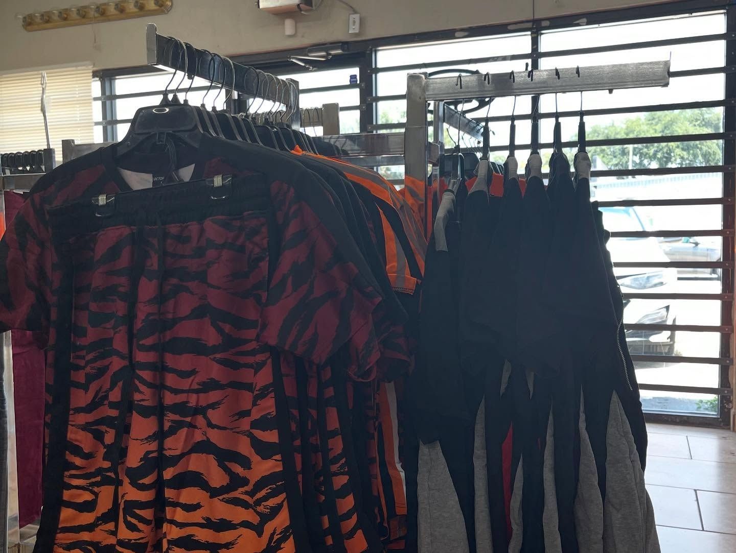 Clothing racks in store, displaying shirts in black, orange, and red patterns.