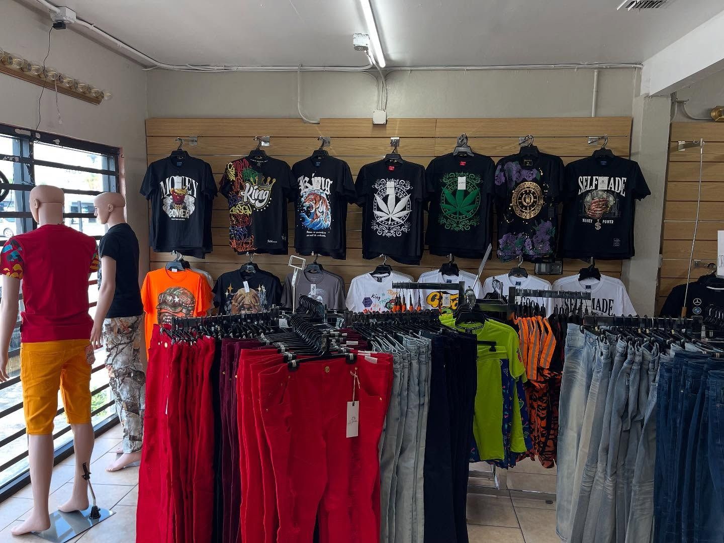 Clothing store display with t-shirts and shorts; mannequins wearing outfits.