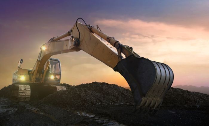 An Excavator Is Digging A Hole In The Ground At Sunset — Sal's Excavations In St. Georges Basin, NSW