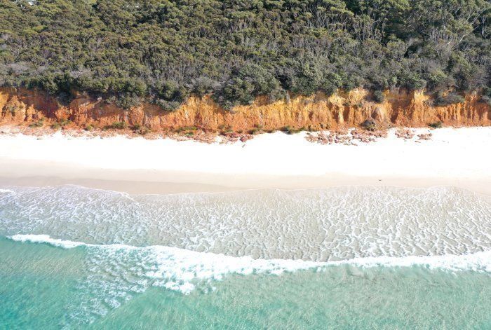 An Aerial View Of A Beach Surrounded By Trees And A Body Of Water — Sal's Excavations In Jervis Bay, NSW