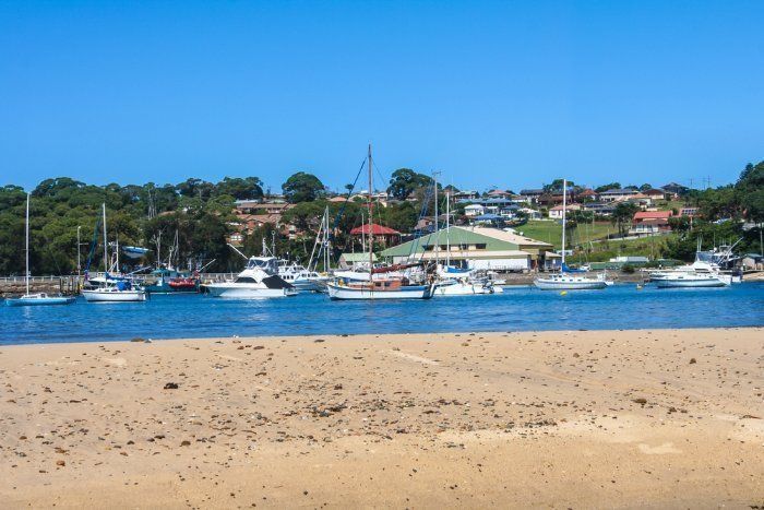A Beach With Boats In The Water And A City In The Background — Sal's Excavations In Ulladulla, NSW