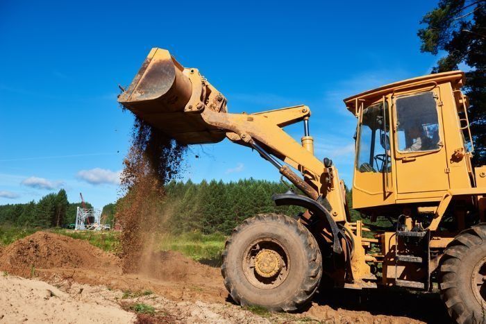 A Yellow Bulldozer Is Loading Dirt Into A Pile — Sal's Excavations In St. Georges Basin, NSW