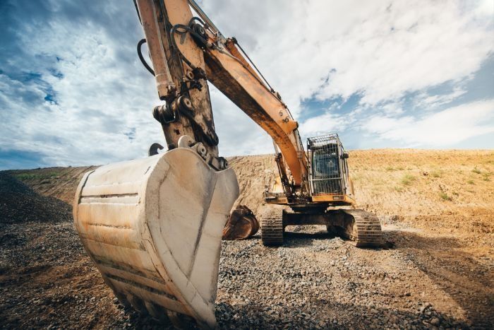 A Large Excavator Is Digging A Hole In A Dirt Field — Sal's Excavations In St. Georges Basin, NSW