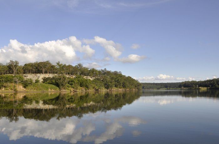 A Lake With Trees On The Shore And Clouds Reflected In The Water — Sal's Excavations In Nowra, NSW