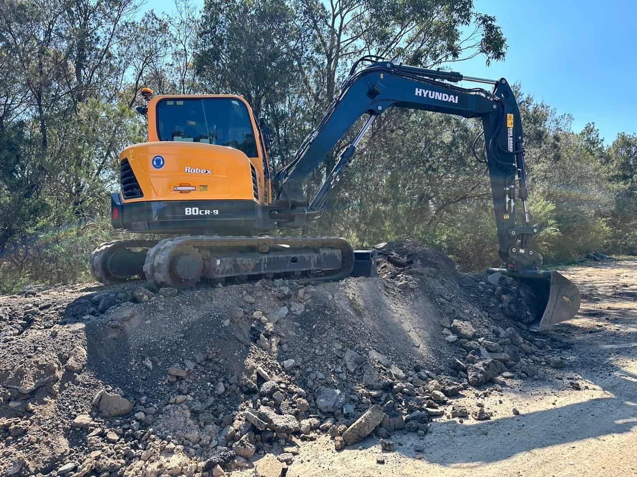 A Yellow And Blue Excavator On Top Of A Pile Of Dirt — Sal's Excavations In Falls Creek, NSW