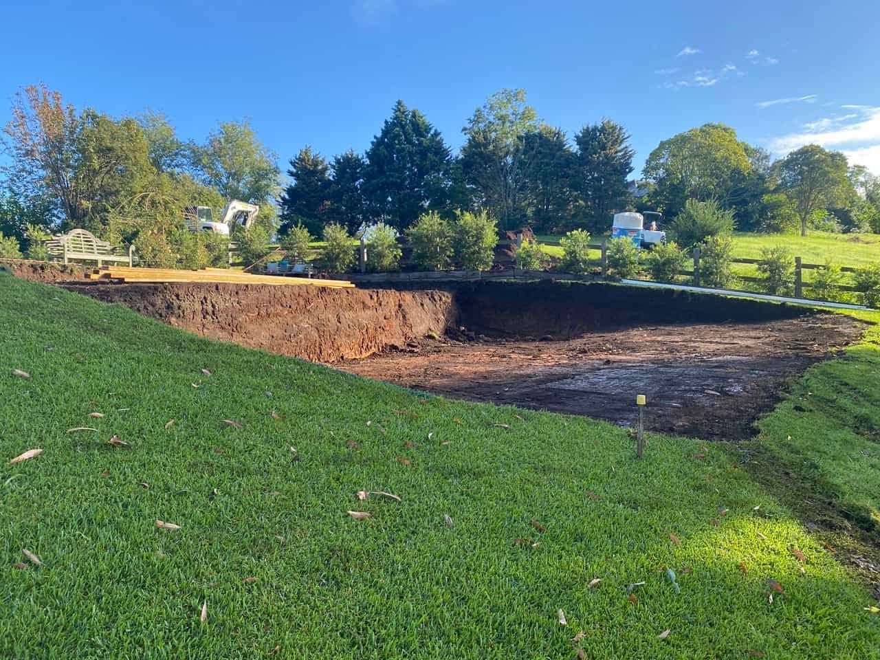 A Large Hole In The Ground In The Middle Of A Lush Green Field — Sal's Excavations In Kiama, NSW