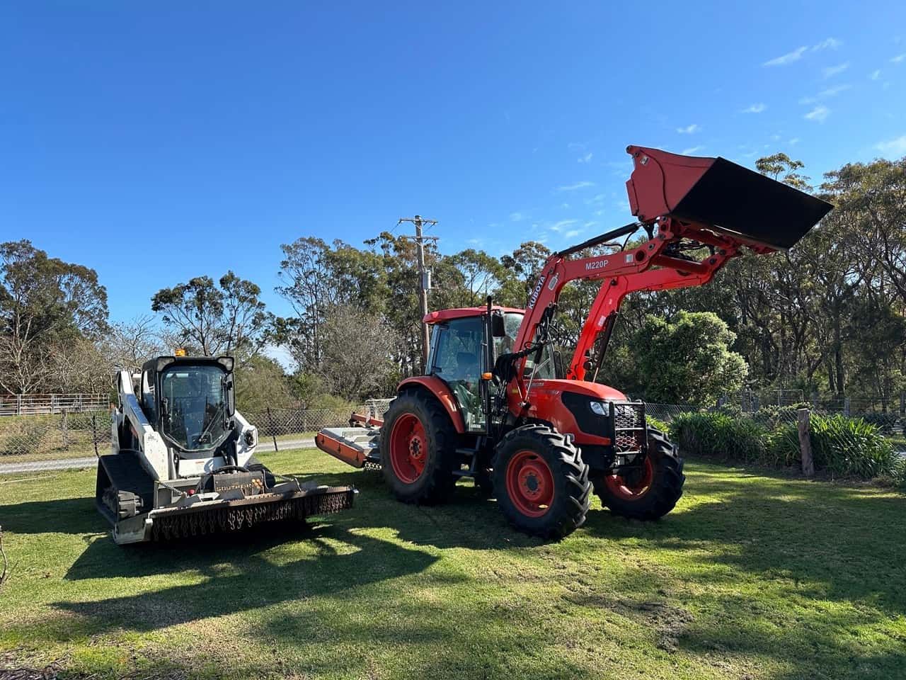 Two Tractors Parked Next To Each Other In A Grassy Field — Sal's Excavations In Ulladulla, NSW