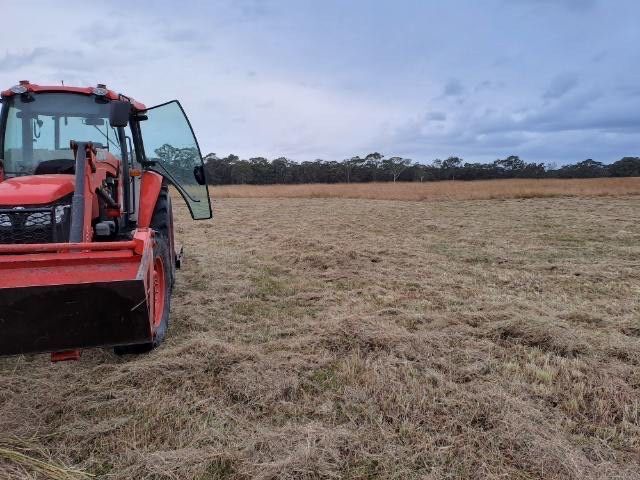 An Orange Tractor Parked In A Field With Its Doors Open — Sal's Excavations In St. Georges Basin, NSW