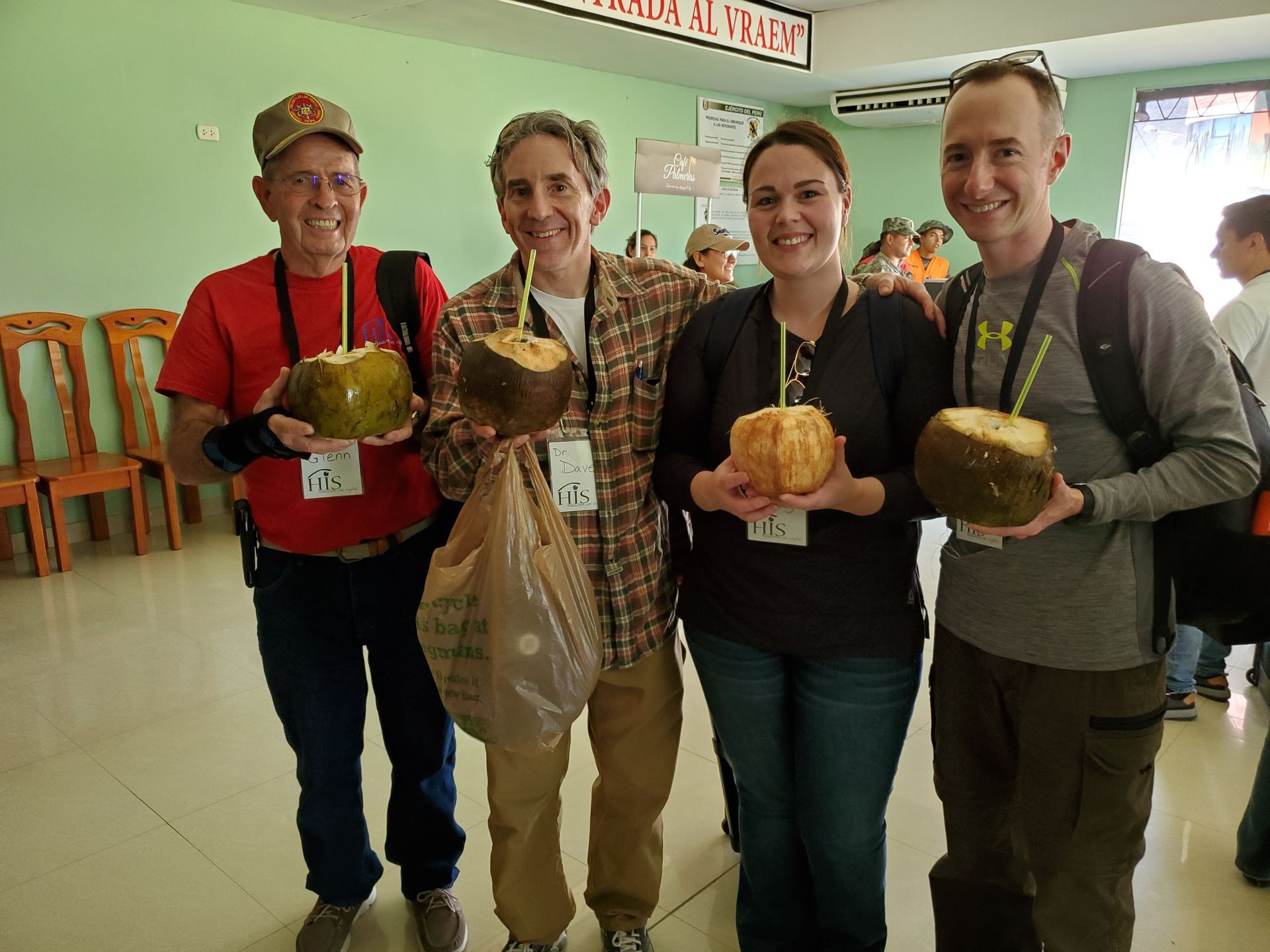 A group of people are posing for a picture while holding coconuts