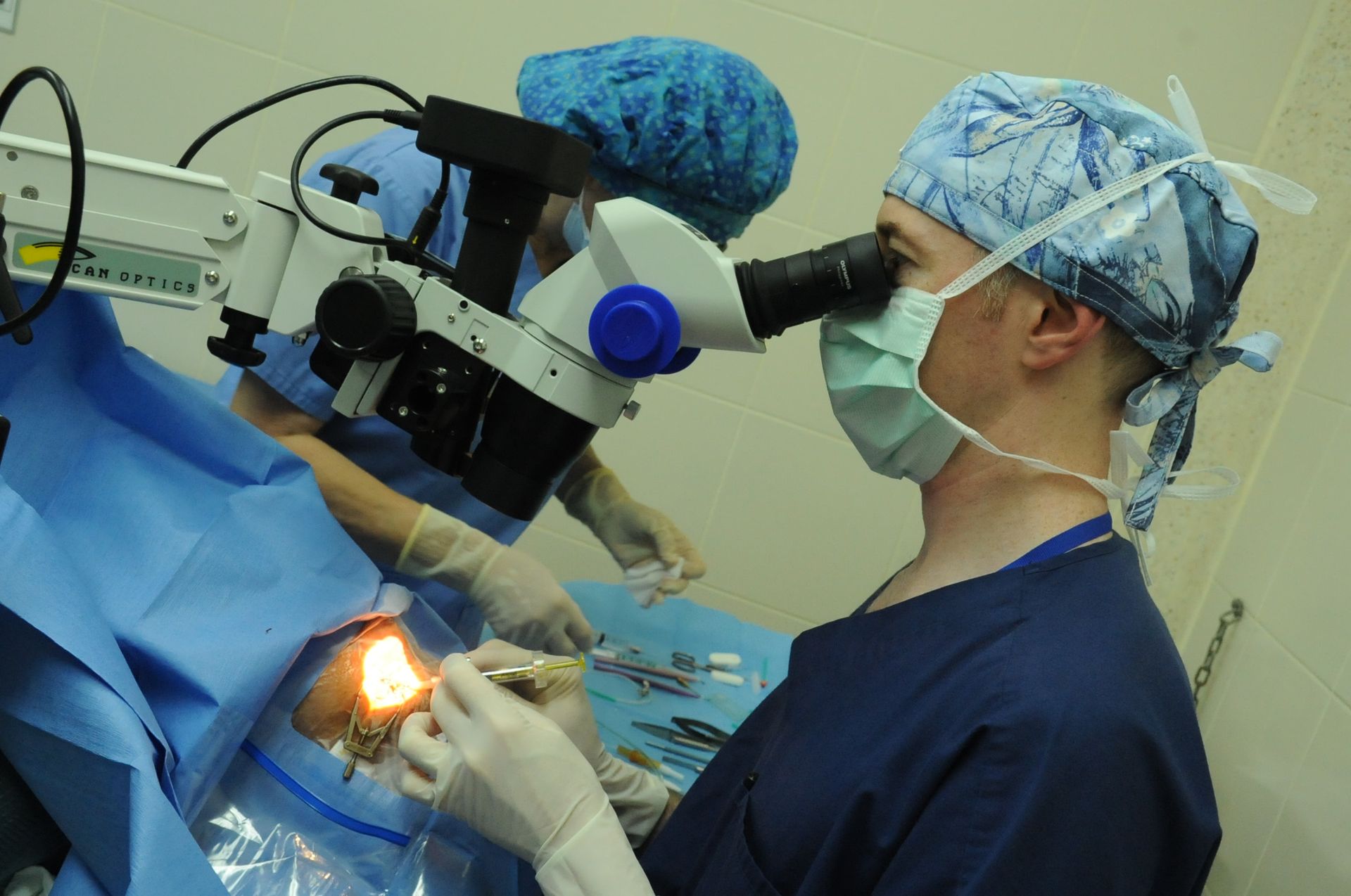 A surgeon looking through a microscope in an operating room