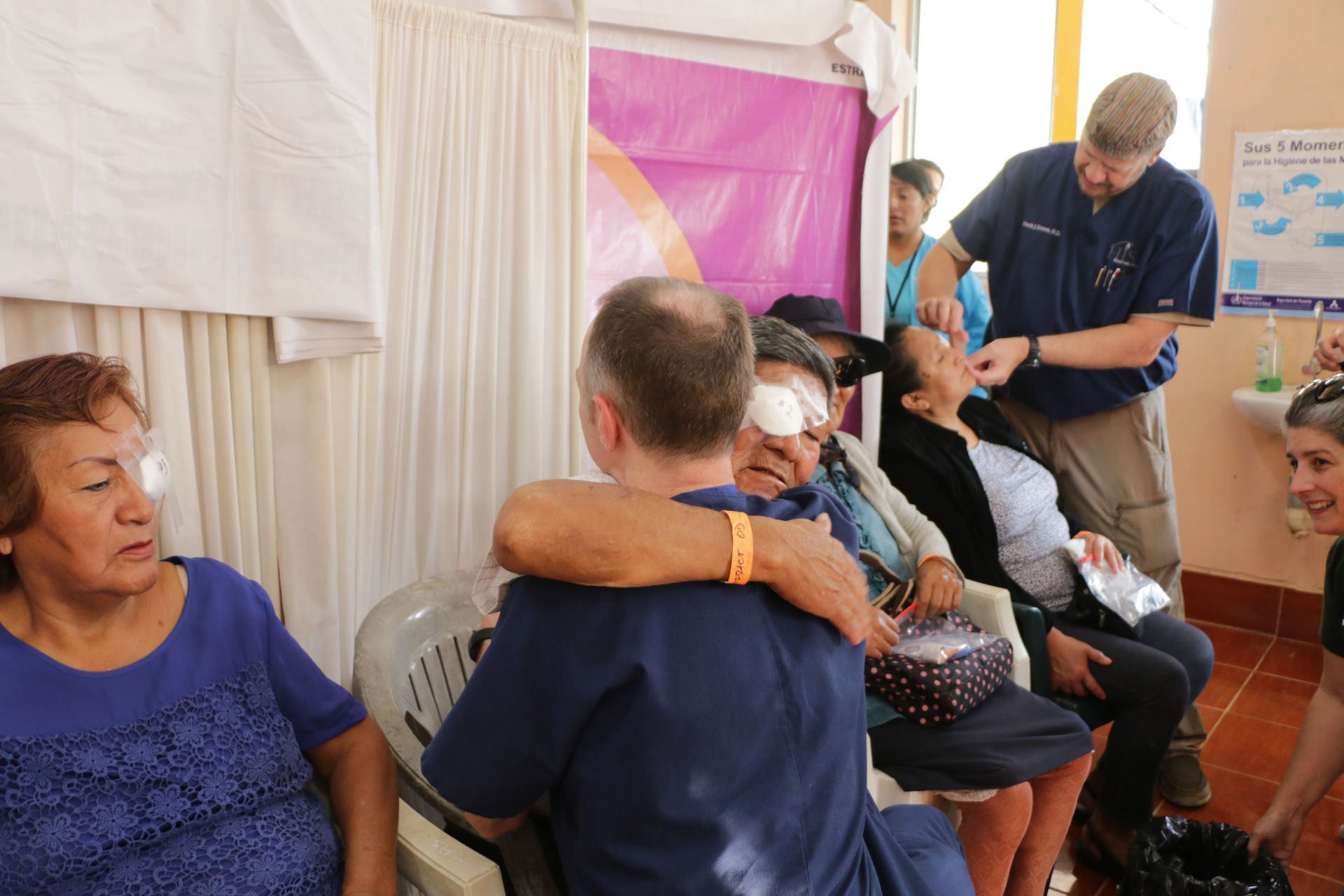 A group of people are sitting in chairs and a man is hugging a woman